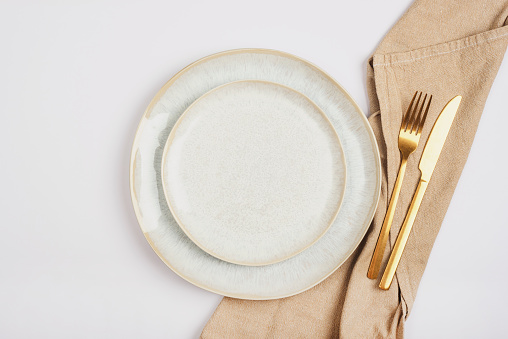 Empty plate and fork and knife with napkin on white background. Table setting. Top view, flat lay.