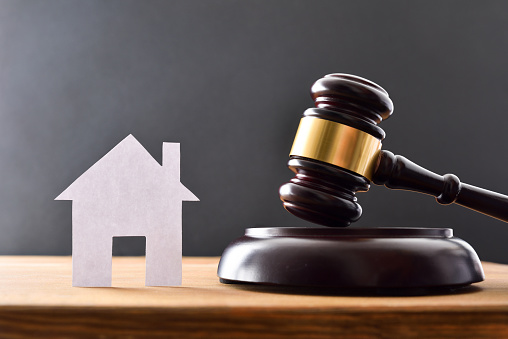 Housing reference judgment concept with house cutout and gavel on wooden table and black isolated background. Front view