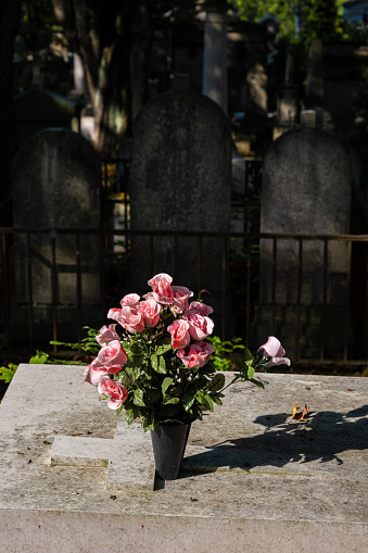 Roses in a vase, on a tombstone at Pere-Lachaise cemetery in Paris, France
