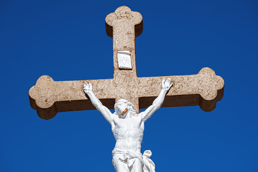 Statue of Christ on the cross against a blue sky in France