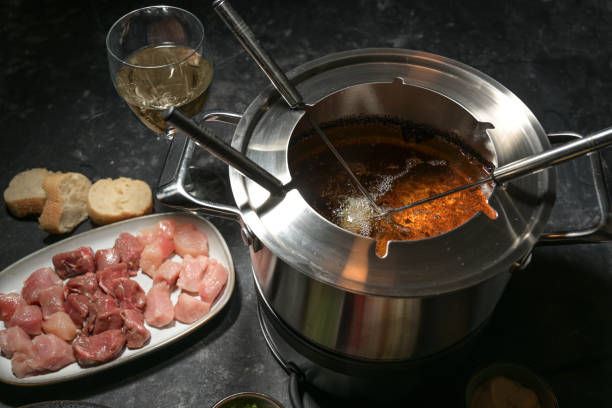 Fondue pot with boiling hot oil, long forks and raw meat, party dinner for friends and family, selected focus stock photo