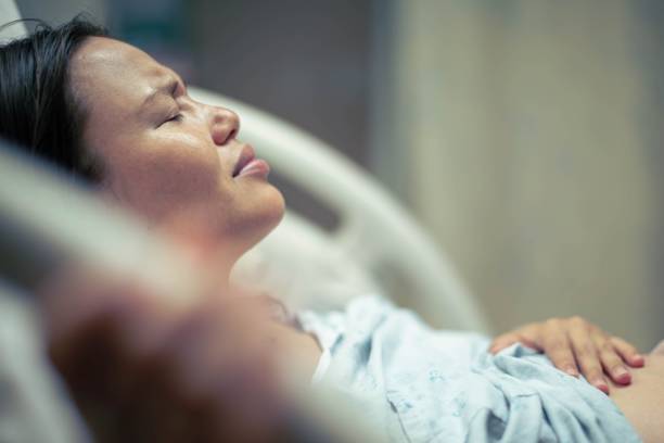 A sick woman patient in bed at the hospital suffering from pain. Contractions and childbirth. stock photo