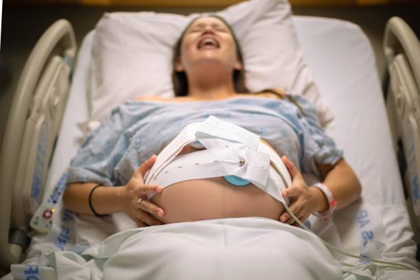 A woman having painful contractions lying in the hospital bed waiting for labor. stock photo