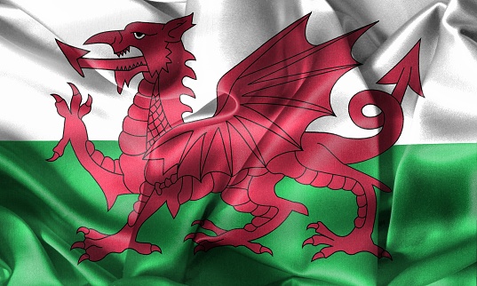 Flag of Wales blowing in the wind. \nFull page Wales flying flag.