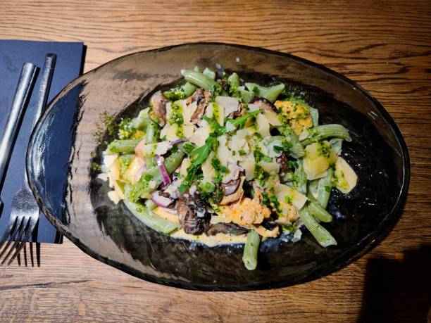 Pollo pesto with chicken breast, portobello and chestnut mushrooms, red onion, chives and basil penne with a creamy sauce of pesto and grana padano cheese  served on a restaurant table