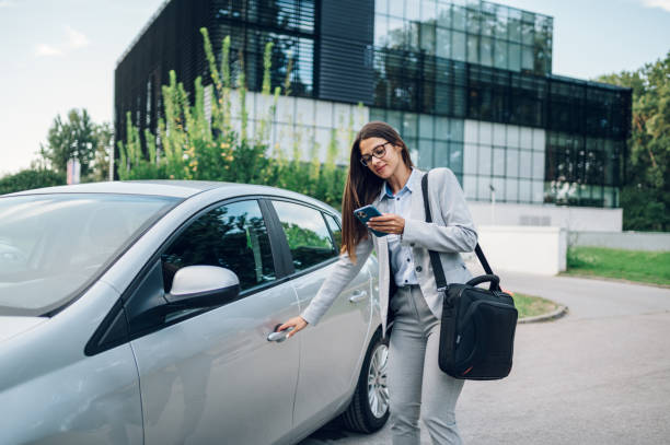 istock Business woman getting into the car and using smartphone 1428849090