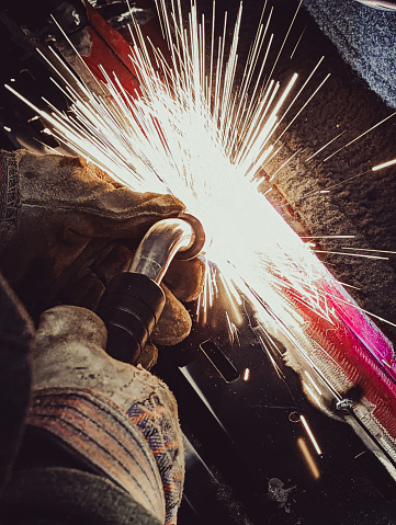 Welding in motion with sparks with red painted metal
