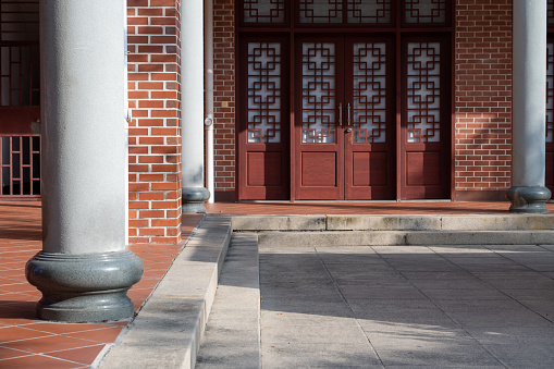 Stone columns and steps in front of Chinese red wooden doors