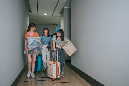 Asian Chinese young women moving in college dorm walking in corridor