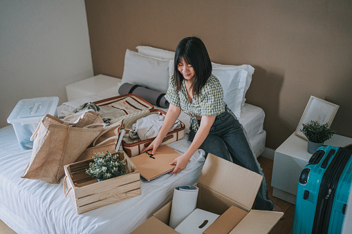 Asian Chinese young woman decluttering unpacking at college dorm room