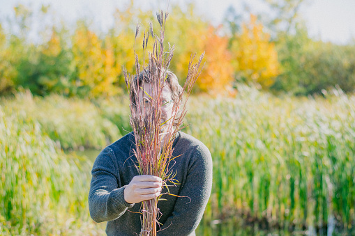 The middle aged man is covering his face with local prairie grass