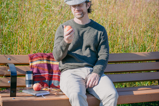 The man is enjoyinga fresh autumn apple while relaxing at the assiniboine forest