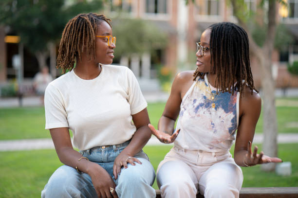 istock Sisters talking and laughing seating at a park 1428906998
