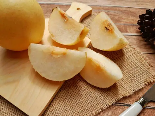 close up of a pear cut into pieces, on a wooden table