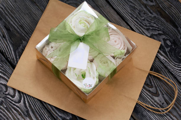 homemade marshmallows in a gift box. tied with ribbon. paper bag from craft paper. zephyr flowers. on black pine boards. taken from above. - craft chocolate candy black box imagens e fotografias de stock