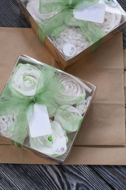 homemade marshmallows in a gift box. tied with ribbon. paper bag from craft paper. zephyr flowers. on black pine boards. taken from above. - craft chocolate candy black box imagens e fotografias de stock