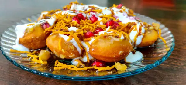 Dahi Puri, a snack popular in India. This dish comes under Chat category. Served in a plate over wooden background. Selective focus