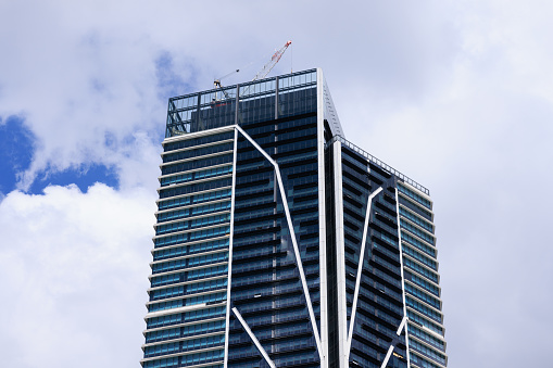 Tall building with cloudy sky and a crane.