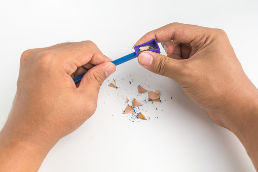 man hand sharpen his blue pencil with pencil sharpener isolated on white background