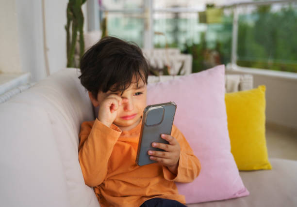 Cute little boy crying because he doesn't want to give the phone back stock photo