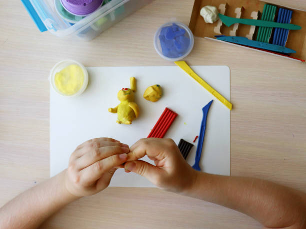 istock The child plays and sculpts figures from plasticine. Children's hands with colored plasticine. Children's games and creativity on vacation. Development of fine motor skills of fingers in children 1428931991
