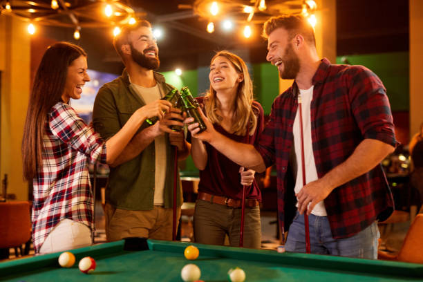 Playing game of pool and drinking beer with friends in local pool hall stock photo