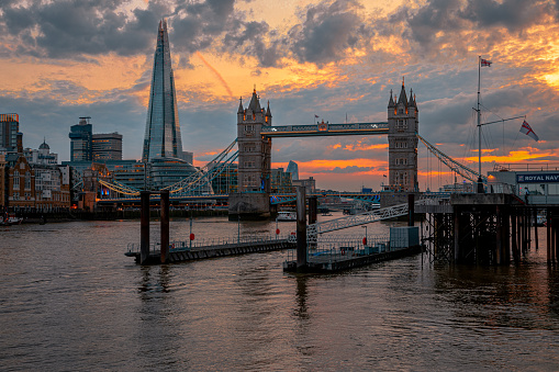 Beautiful during sunrise with illuminated buildings on the River Thames at Tower Bridge and Financial district in City of London, England.