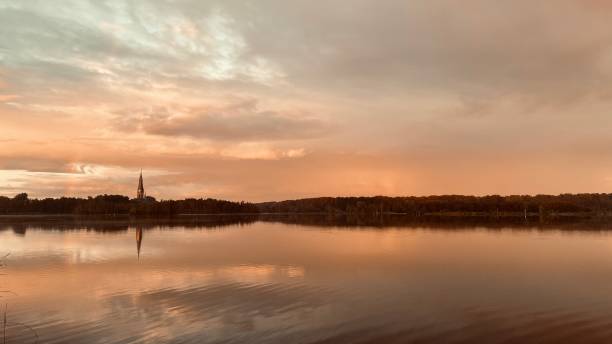 Regenboog gereflecteerd in water in het Amsterdamse bos met de kerk van Bovenkerk.