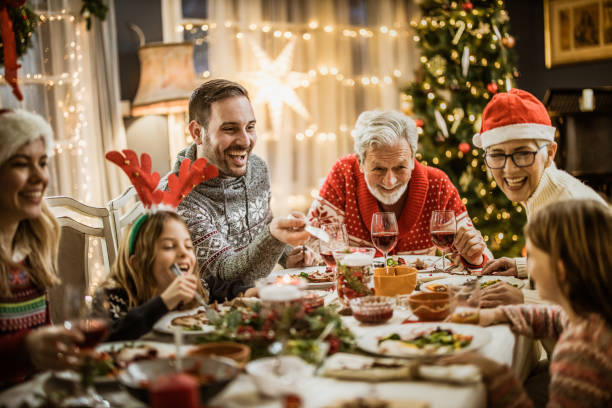 Happy extended family having New Year's lunch at dining table. Happy multi-generation family talking while having New Year's meal at dining table. merry christmas family stock pictures, royalty-free photos & images