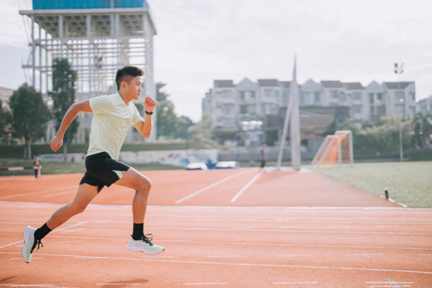 Young asian Chinese man athlete training on running track in the morning at track and field stadium Young asian Chinese man athlete training on running track in the morning at track and field stadium running shorts stock pictures, royalty-free photos & images