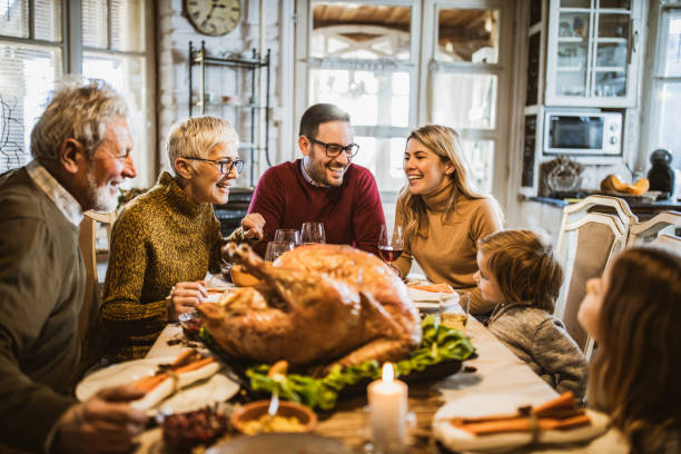 felice famiglia allargata che parla durante il pasto del ringraziamento al tavolo da pranzo. - stuffed turkey foto e immagini stock