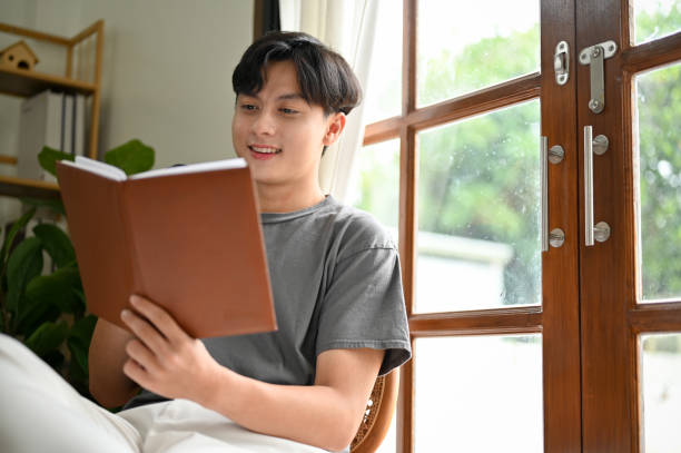 istock Smart young Asian man reading a book, researching information on a textbook 1428943525