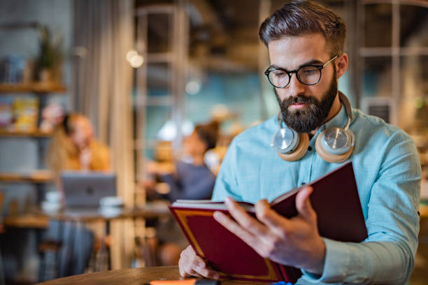 istock Man reading a book in university cafe 1428947739