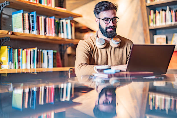 Male student using laptop in the library stock photo