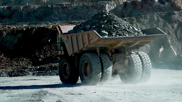 Heavy mining dump trucks driving along the opencast open mine pit, slow motion