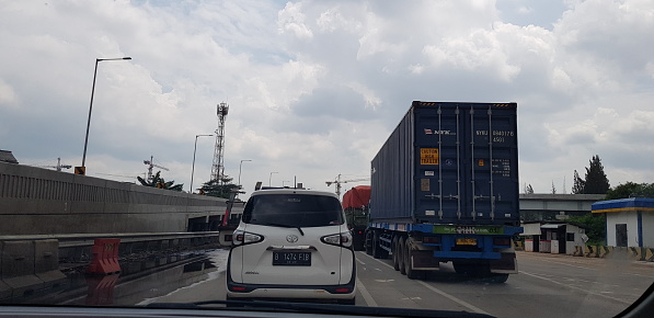 Jakarta, Indonesia in August 2019. Rear view photo of a car and truck box in a toll road jam. Vehicles run slowly and sometimes stop, there are hawkers selling.