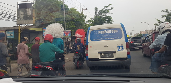 West Java in April 2019. Rear view of motorbikes and cars in an arterial road jam. When traffic jams, the vehicle runs slowly and even stops temporarily.