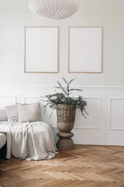 istock Christmas interior. Two blank vertical wooden picture frames mockups. White wall background.. Bed, sofa with linen cushions, blanket. Larch, pine tree branches in wicker basket, wooden coffee table. 1428954723