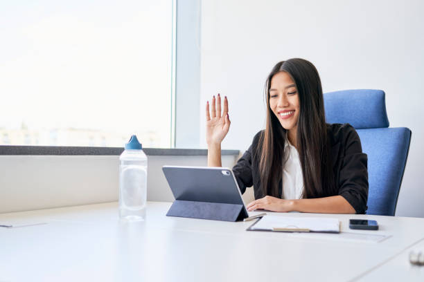 istock Smiling young woman waving during video call at office 1428954853