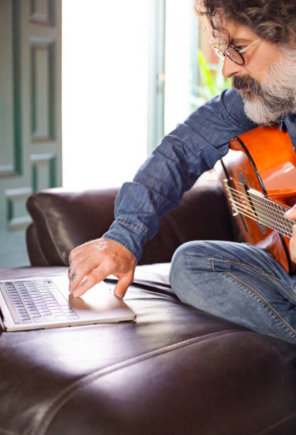 istock Middle-aged man taking guitar lessons at home. 1428959842