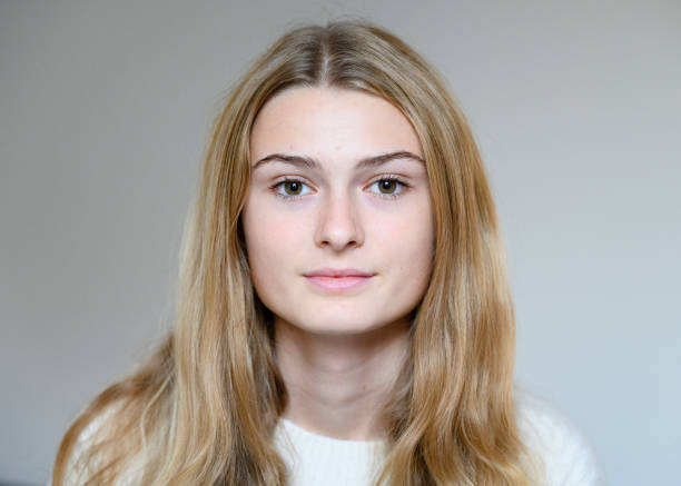 Headshot portrait of 14 year old Caucasian girl Close up of real teenage girl looking to camera against a plain background london girl stock pictures, royalty-free photos & images