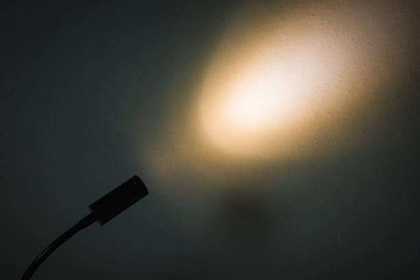 istock Dark scene of small lamp shining on concrete wall. 1428971106