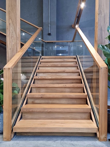 The stairs are made of wood in a modern, elegant style. The railings are made of laminated glass and wood.