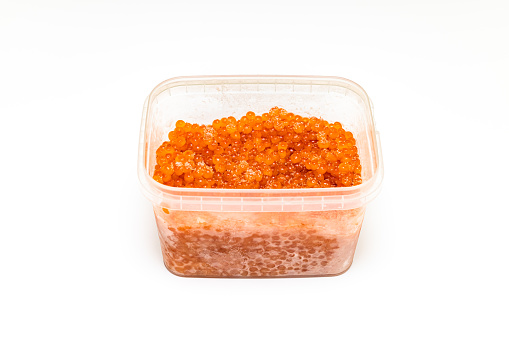 red caviar in a plastic container on a white background. frozen caviar