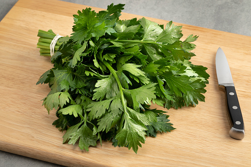 Bunch of fresh green celery leaves on a cutting board close up