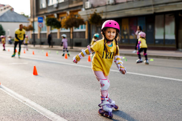 Cute little girl practicing roller skating in the city