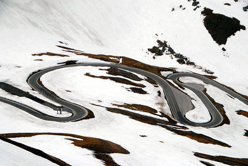 switchbacks of mountain road in springtime with rests of snow