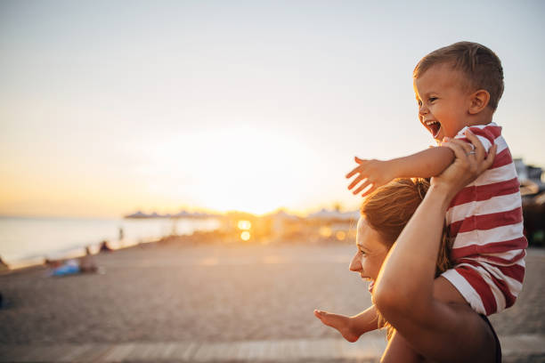 息子を浜辺で運ぶ母親 - beach mother family playful ストックフォトと画像