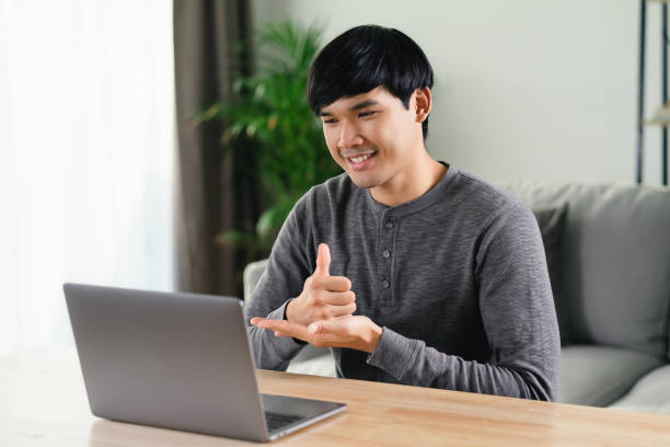 istock Young Asian man deaf disabled using laptop computer for online video conference call learning and communicating in sign language. 1428987759