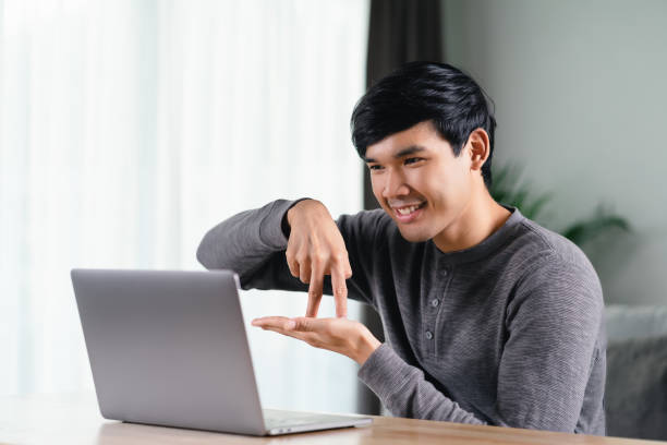 istock Young Asian man deaf disabled using laptop computer for online video conference call learning and communicating in sign language. 1428987812